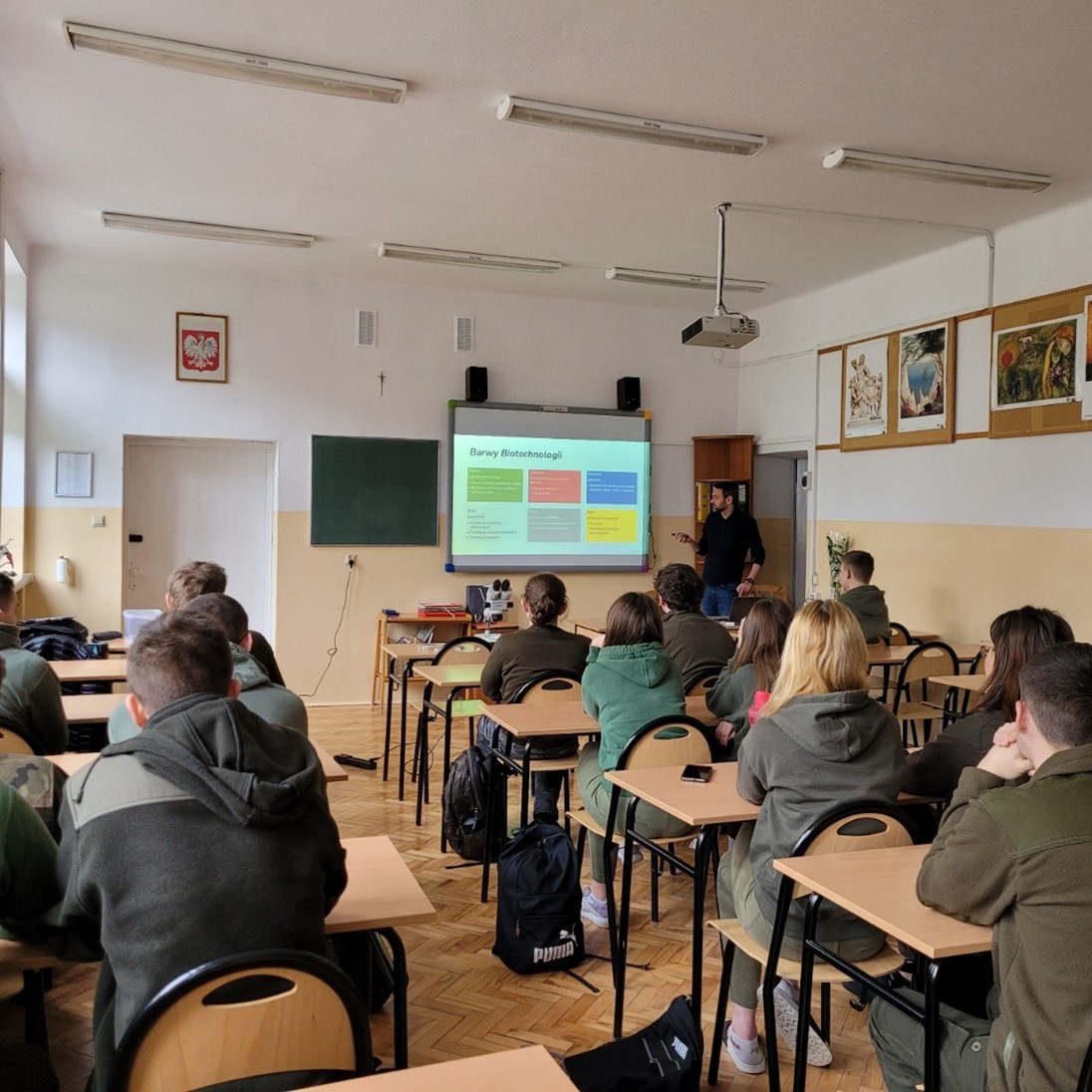 W sali lekcyjnej  w Zespole Szkół Leśnych w Zagnańsku  mężczyzna - przedstawiciel UJK wygłasza prezentację na temat oferty kształcenia na kierunku Rolnictwo. Uczniowie siedzą w ławkach i oglądają prezentację.