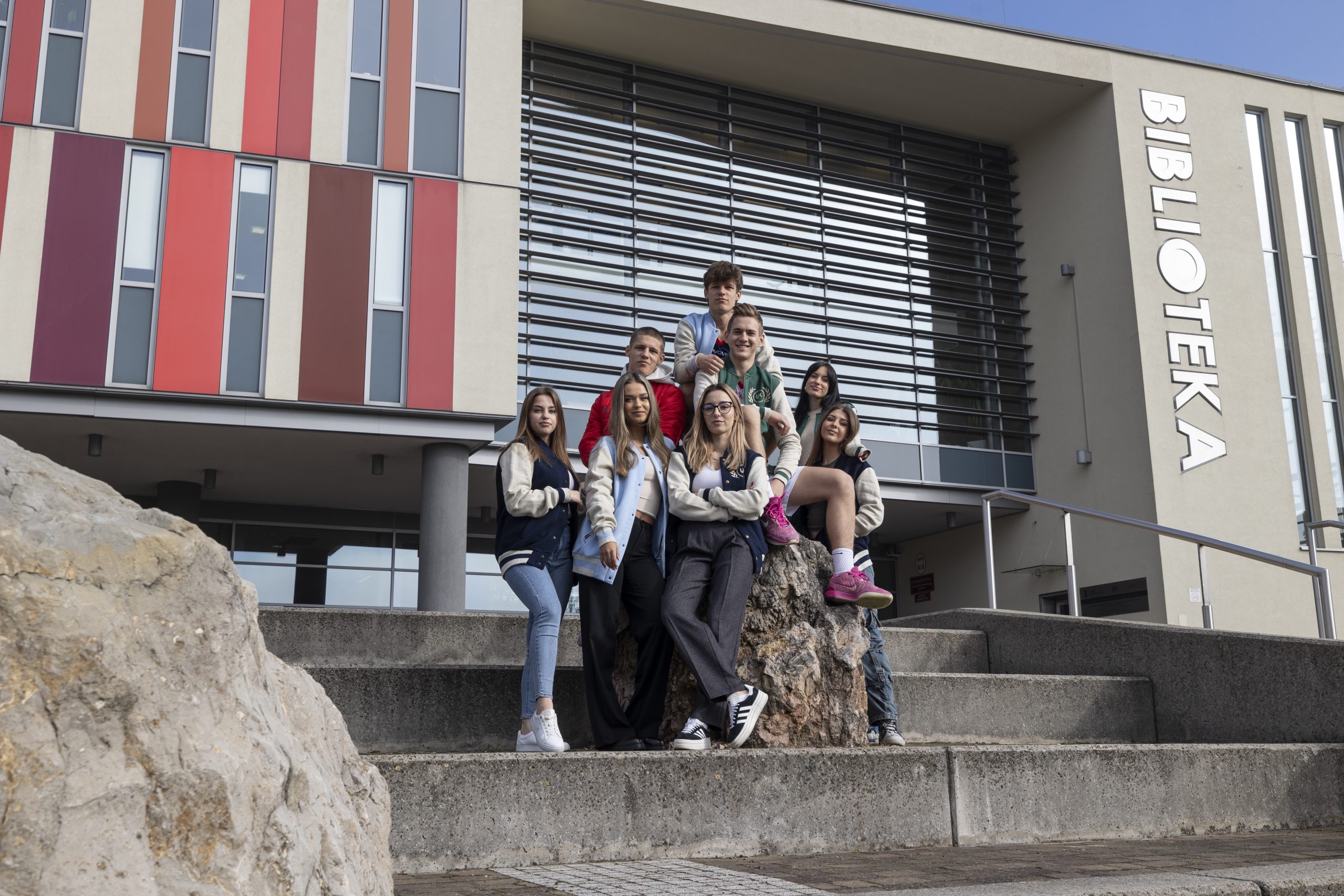 Grupa studentów stoi przed budynkiem Biblioteki Uniwersyteckiej UJK.