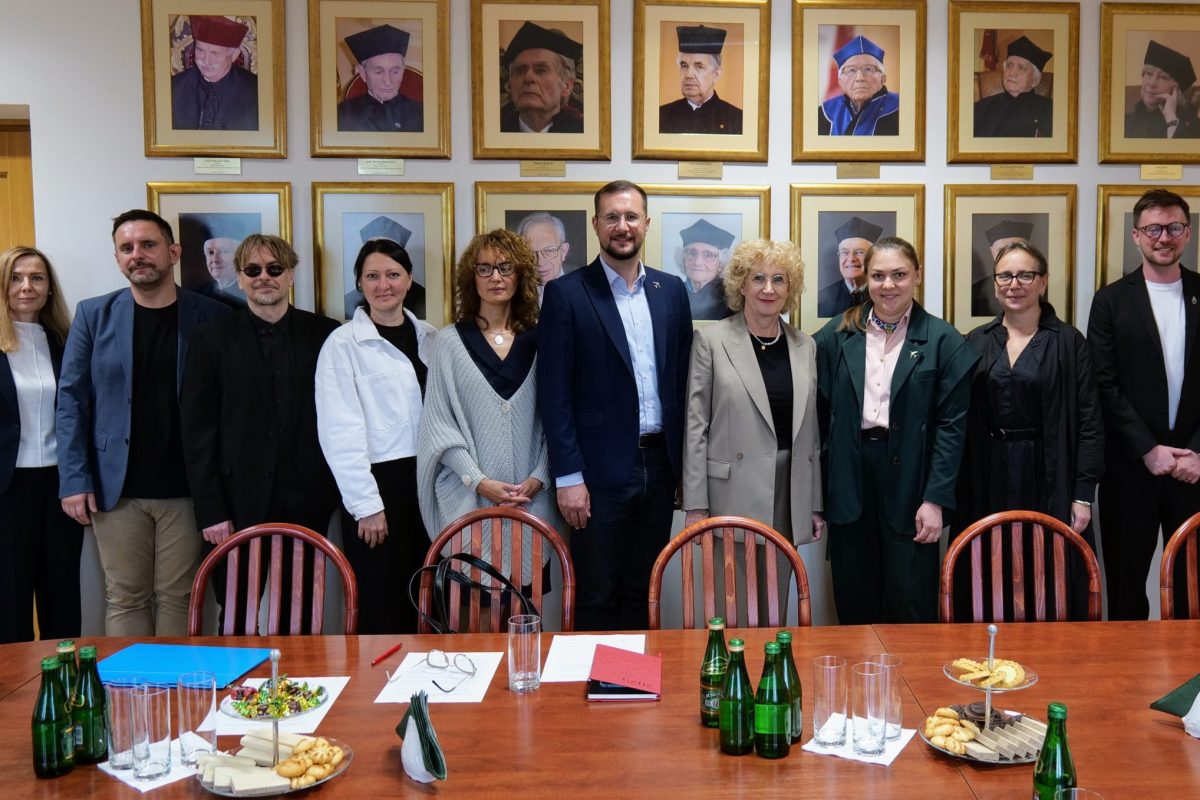 Uczestnicy spotkania. W tle portrety doktorów honorowych UJK.