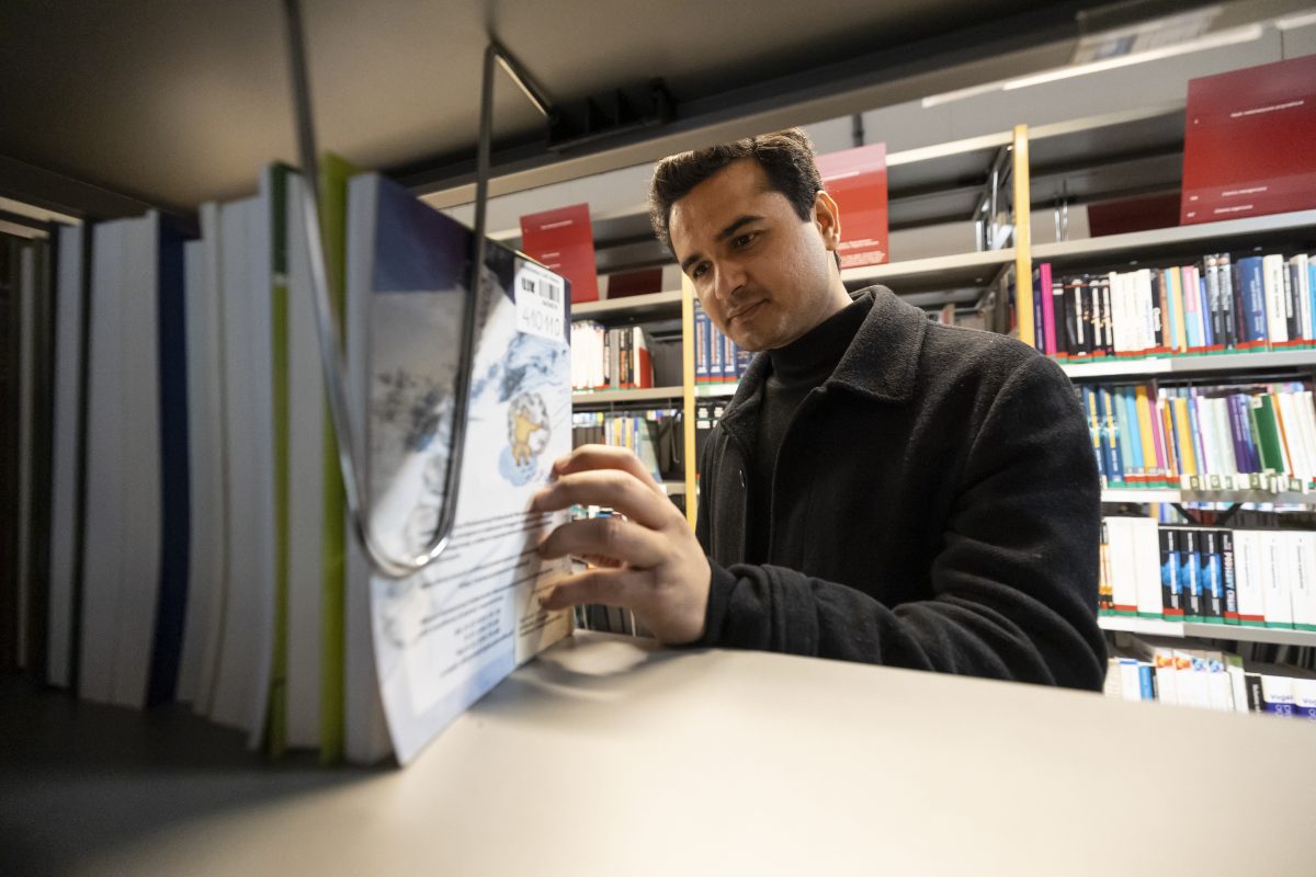 Meżczyzna sięgający po dokumenty na półce bibliotecznej