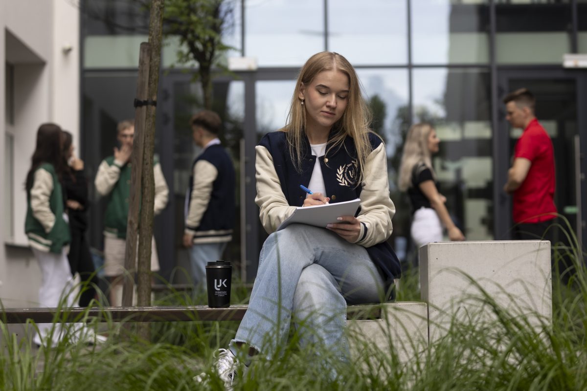 Studentka robiąca notatki na ławce przed uczelnią
