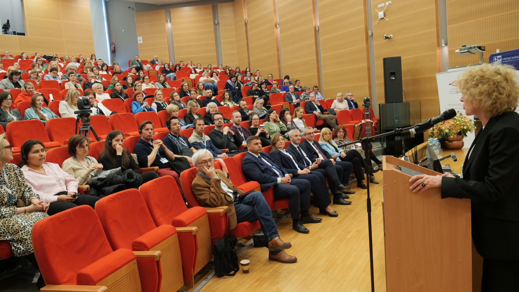 Przy mikrofonie prof. Beata Wojciechowska, rektor UJK. W tle audytorium konferencji.