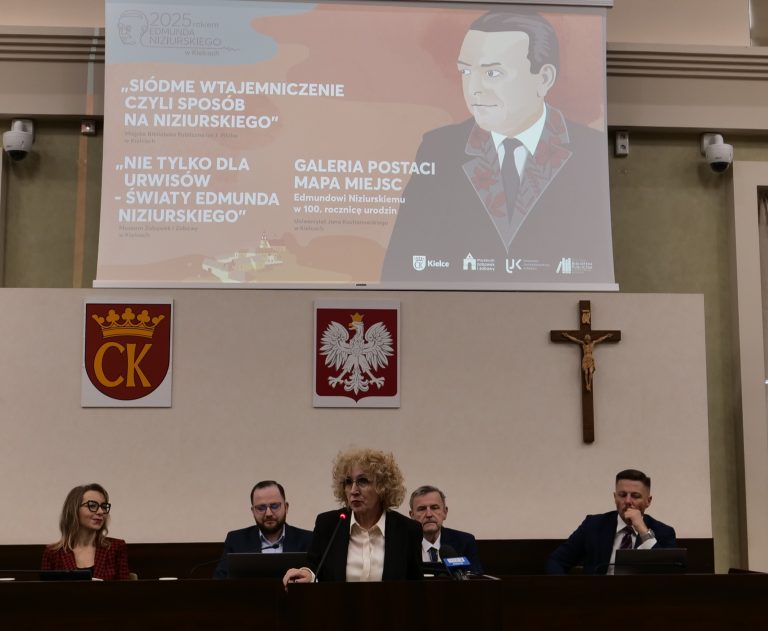 Sesja Rady Miasta w Kielcach. Przemawia prof. Beata Wojciechowska, rektor UJK. W tle prezydium Rady i plakat okolicznościowy.