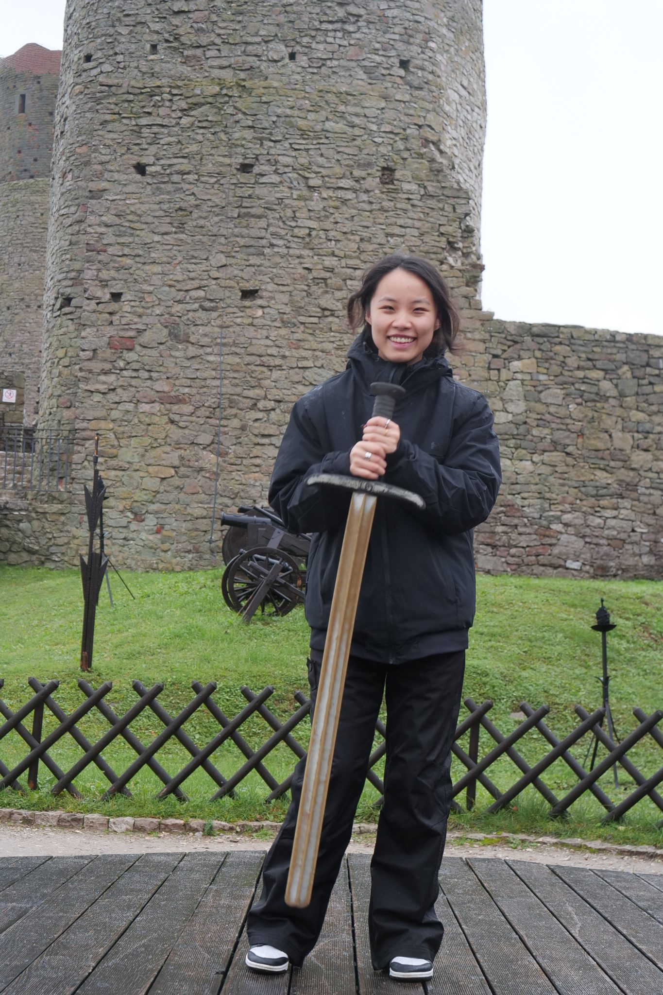 Studentka wymiany międzynarodowej z mieczem na tle Zamku Królewskiego w Chęcinach.