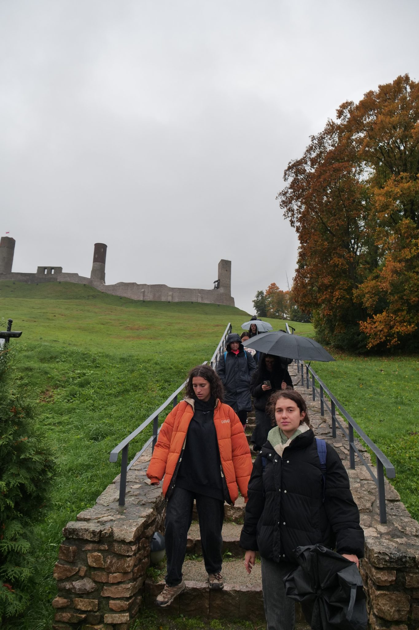 Grupa studentów wymiany międzynarodowej schodzi po schodach przed Zamkiem Królewskim w Chęcinach.