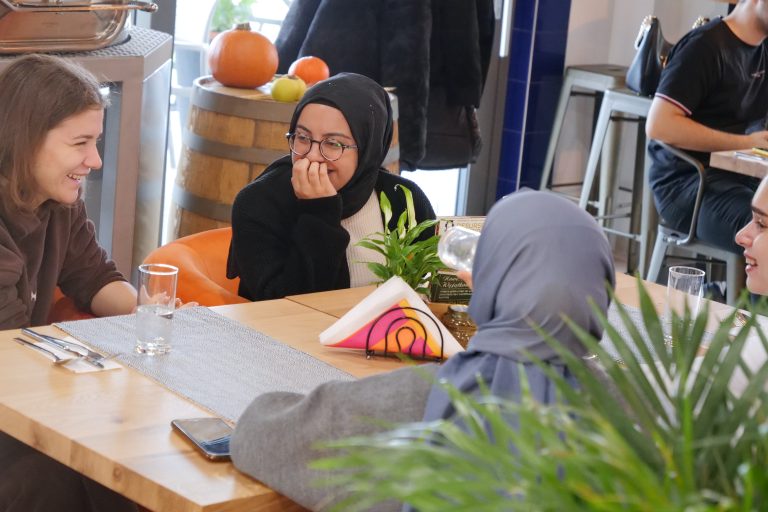 Dwie studentki w chustach siedzą przy stole w restauracji.