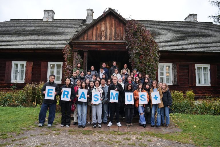 Grupa studentów wymiany międzynarodowej w skansenie w Tokarni trzymają napis Erasmus+.