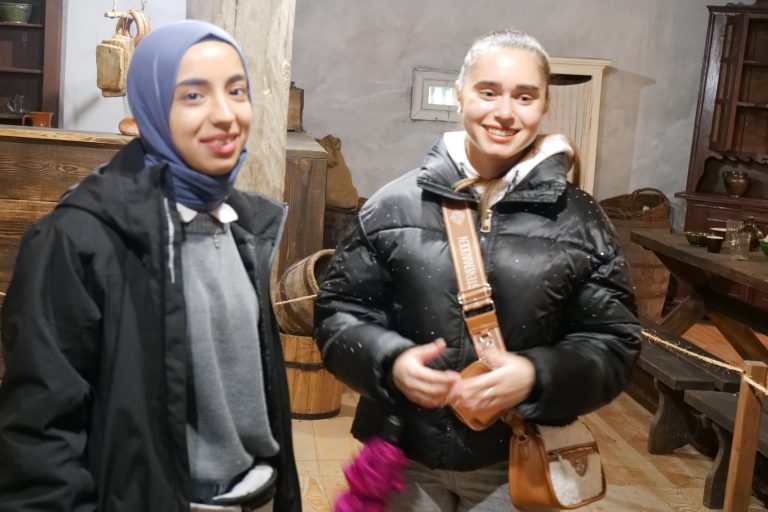 Dwie studentki uśmiechają się i pozują do zdjęcia.