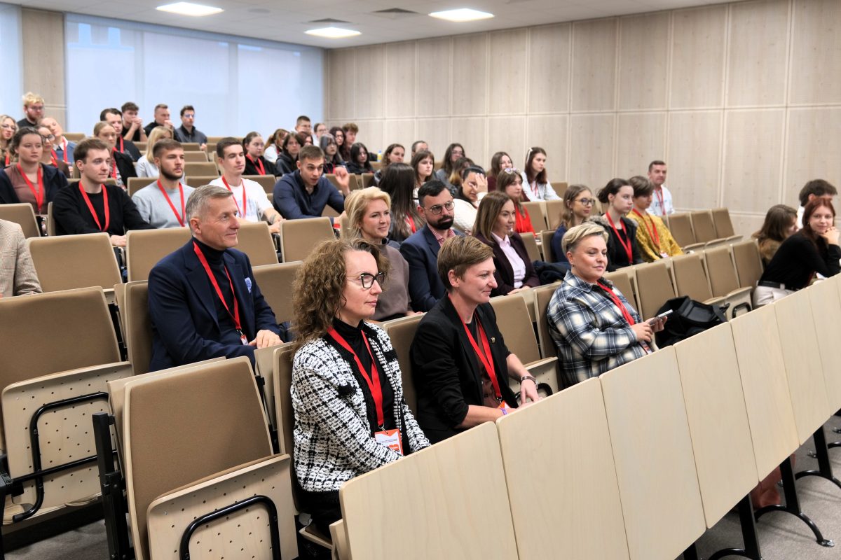 Wiele osób zajmujących miejsca na sali wykładowej
