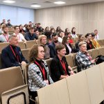 Wiele osób zajmujących miejsca na sali wykładowej