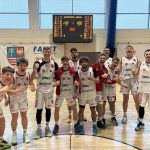 Grupa koszykarzy w białych strojach &bdquo;UJK Kielce&rdquo; cieszy się na parkiecie po wygranym meczu. Zawodnicy krzyczą, wykonują gesty zwycięstwa i uśmiechają się. W tle tablica wynik&oacute;w wskazuje 110:100.