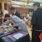 Studenci przy stoisku z ulotkami o profilaktyce ryzykownych zachowań seksualnych