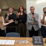Prof. Kiebzak ze studentami prezentuje prawidłową postawę ze smartfonem.